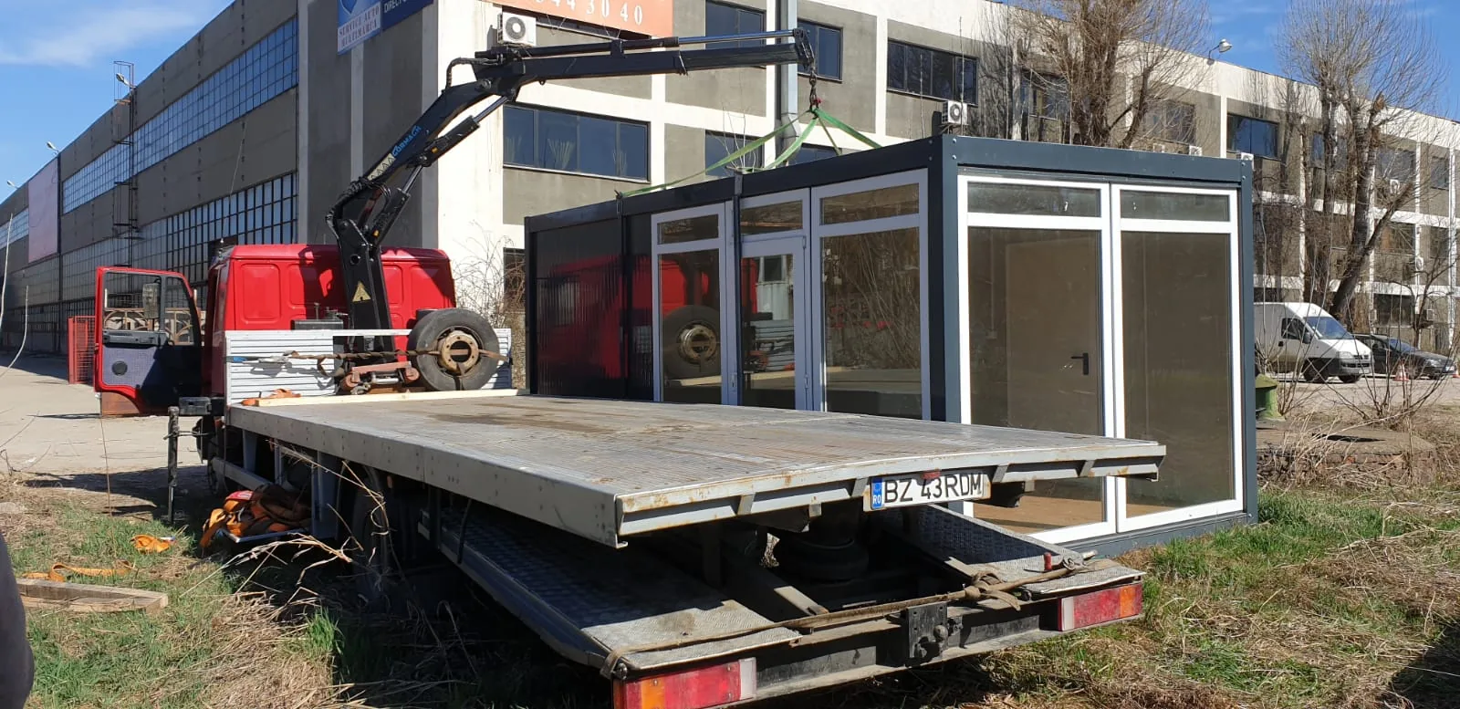 Birou modular urcat pe platformă, cu macaraua alături.