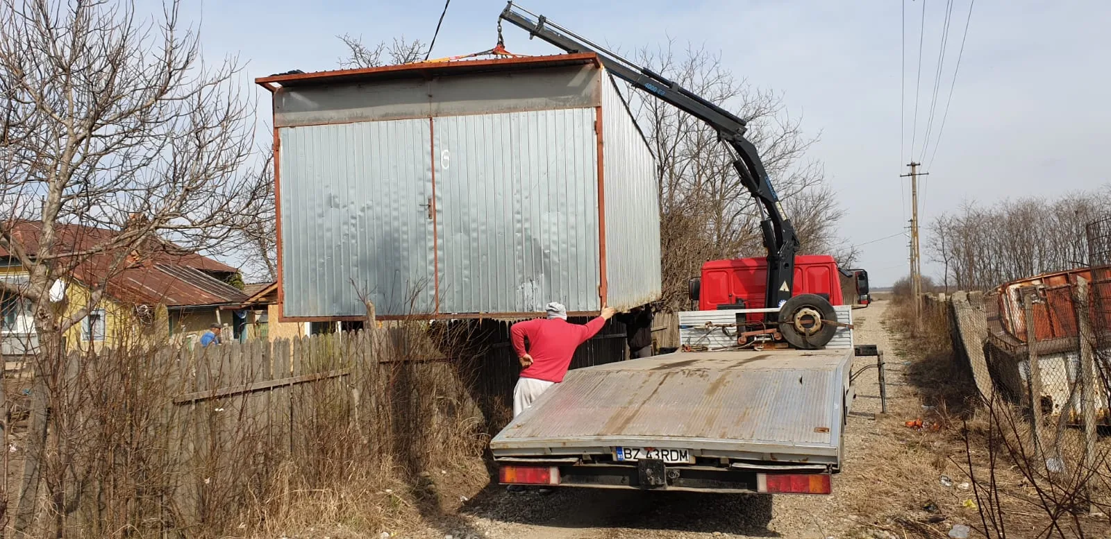 Container metalic ridicat cu macaraua, direct pe platformă.