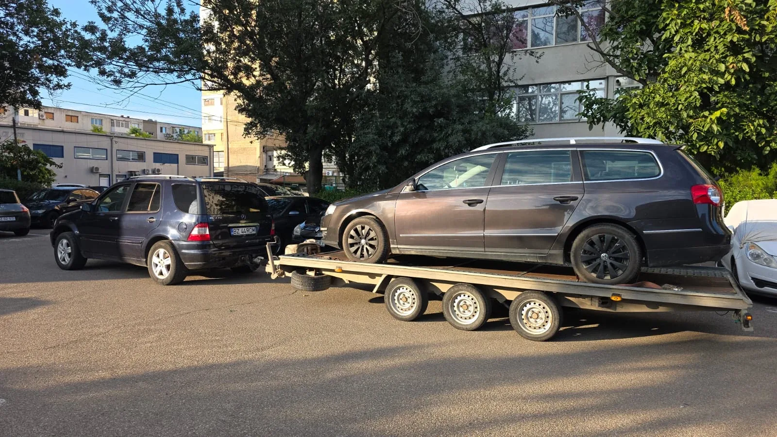 Un Volkswagen Passat break pe remorca-platformă cu trei axe, la apus.